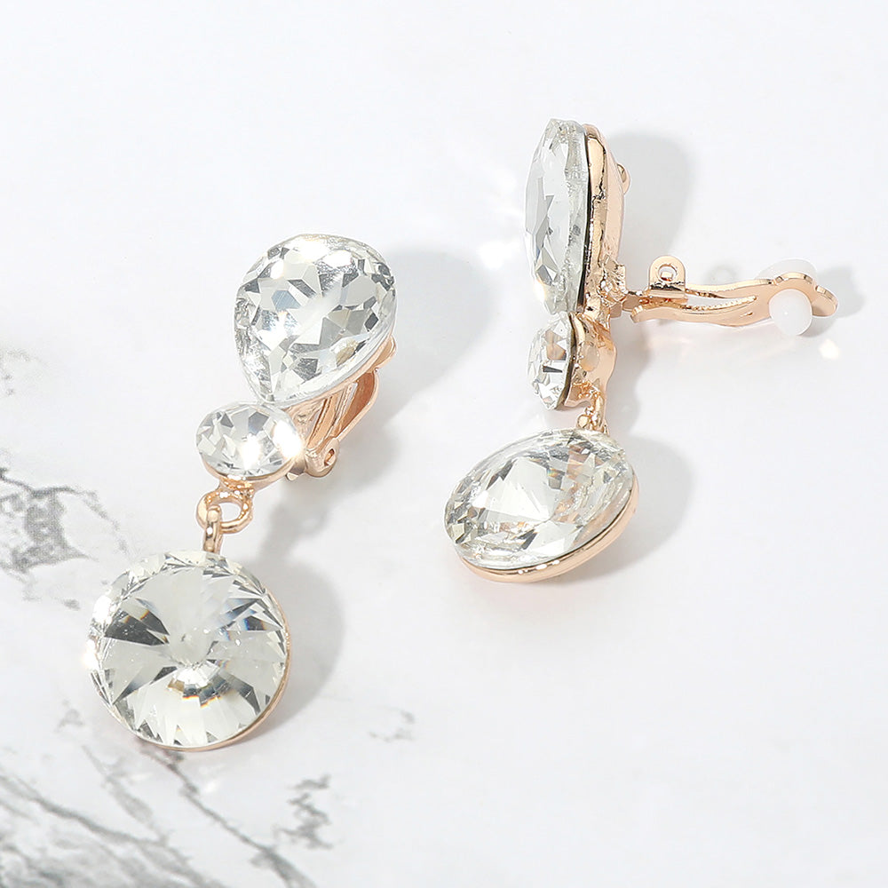 Clear round crystal drop clip-on earrings on gold on white marble background