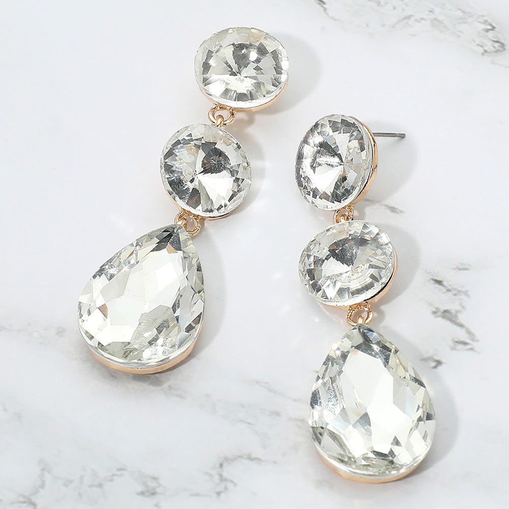 Clear round and teardrop cluster earrings on gold for weddings, interviews, or evening glam on a marble background