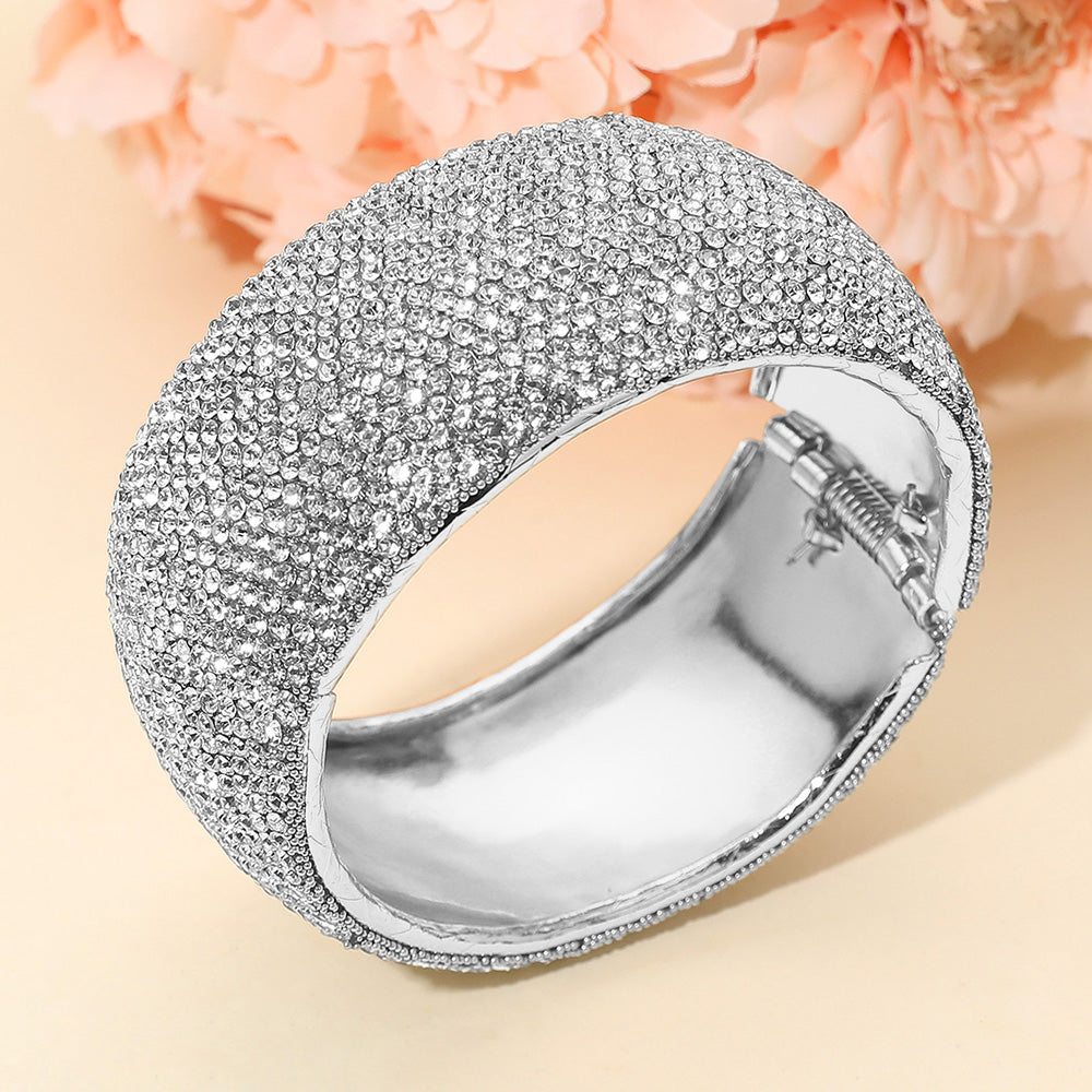 Clear crystal wide rhinestone hinged evening bangle bracelet on silver with pavé design on a peach background