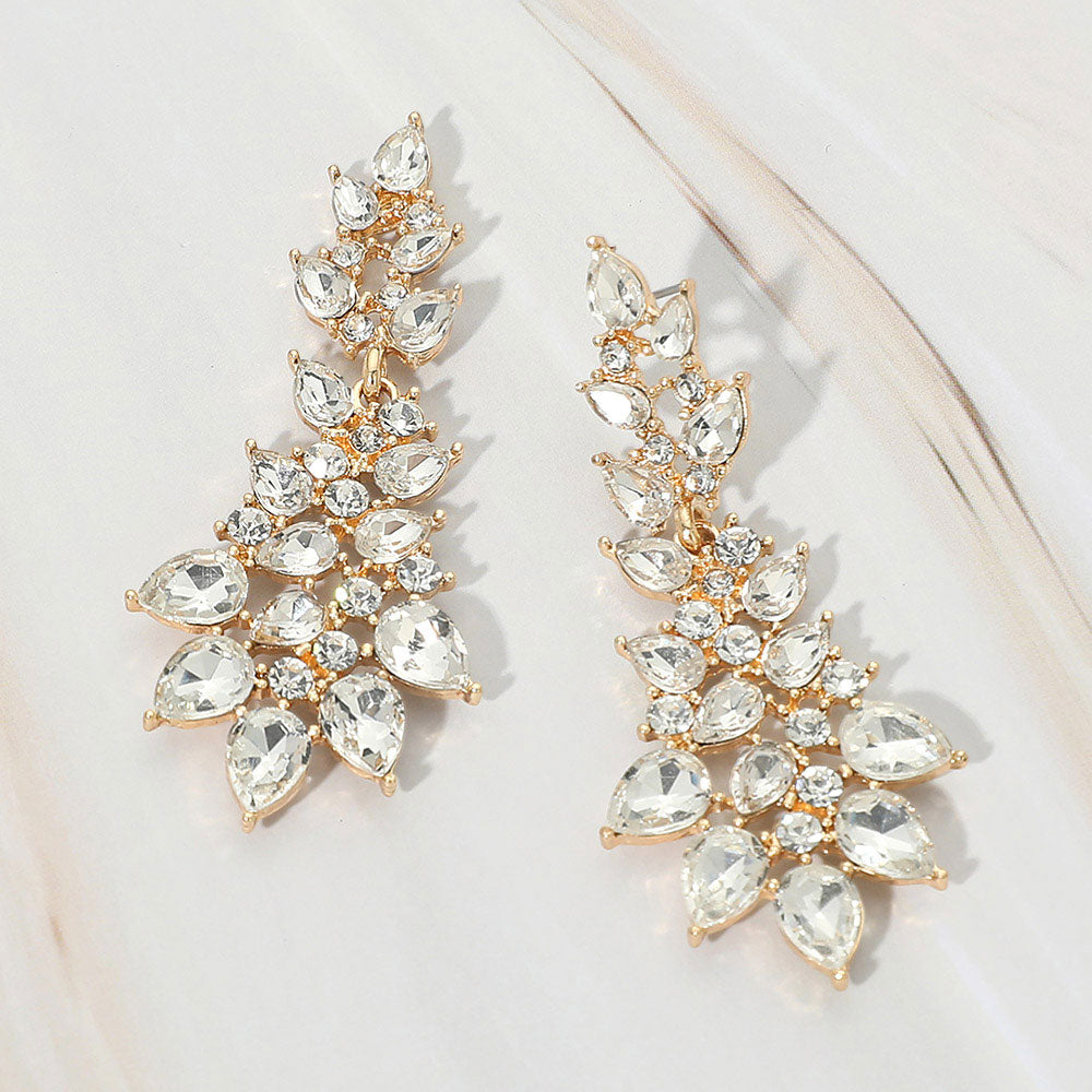 Clear teardrop cluster drop earrings on gold with faceted stones on white marble background