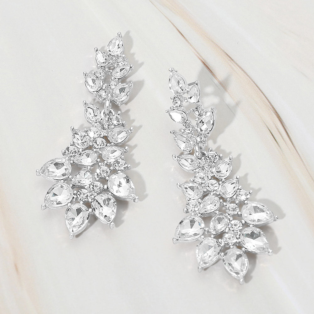 Clear teardrop cluster drop earrings on silver with faceted stones on white marble background