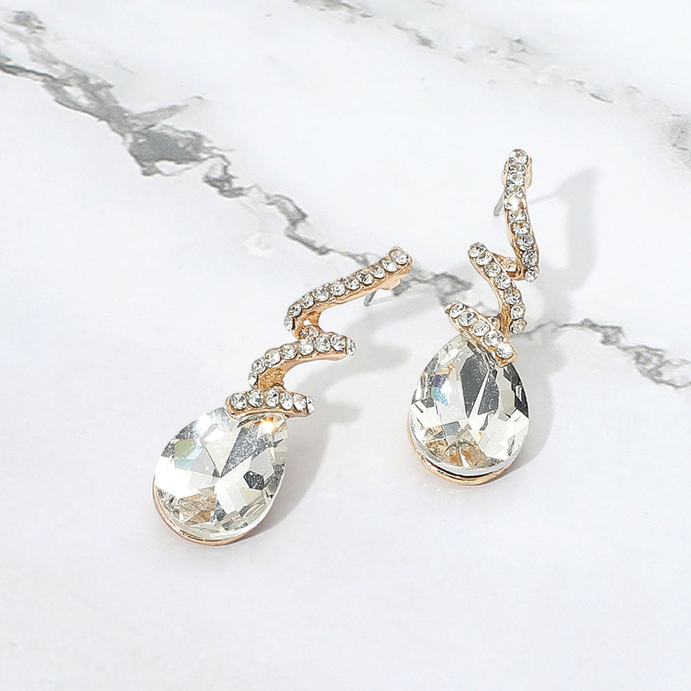 Clear on gold teardrop swirl crystal earrings on gold for girls pageant or holiday wear on a white background