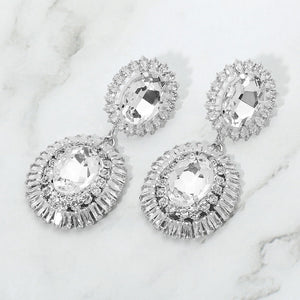 Clear vintage double oval crystal statement earrings in a silver finish featuring two oval clear crystals surrounded by sparkling crystal halos, displayed on a white marble background.