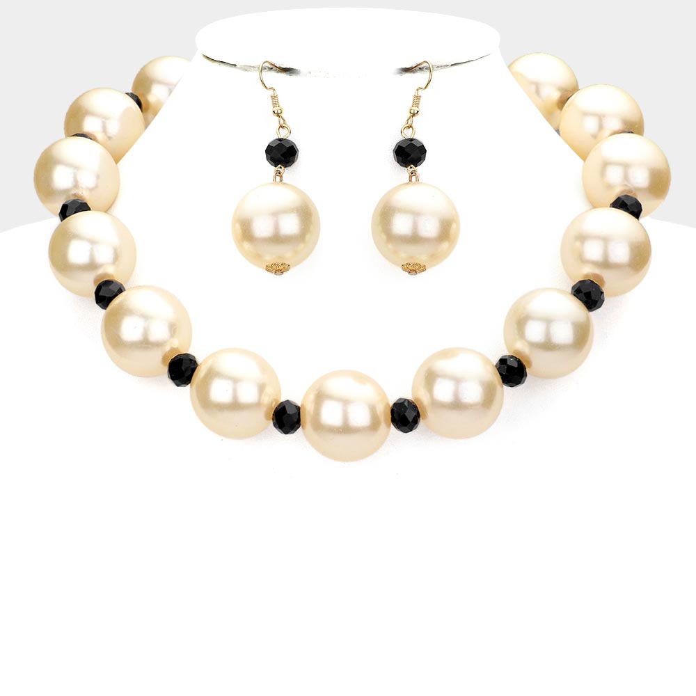 Cream oversized pearls, divided by black accent beads, and matching drop earrings, statement necklace set, displayed on a white jewelry bust.