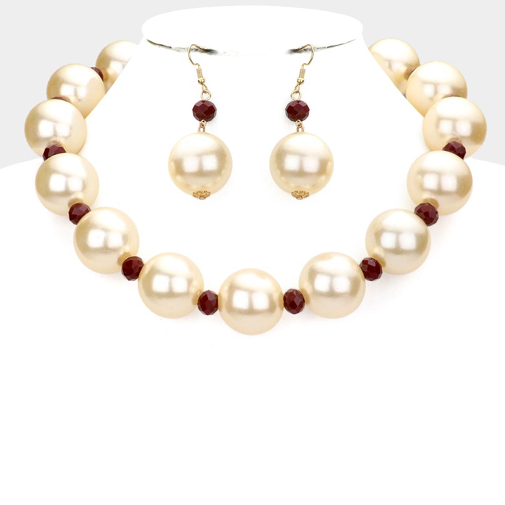 Cream oversized pearls, divided by burgundy accent beads, and matching drop earrings, statement necklace set, displayed on a white jewelry bust.