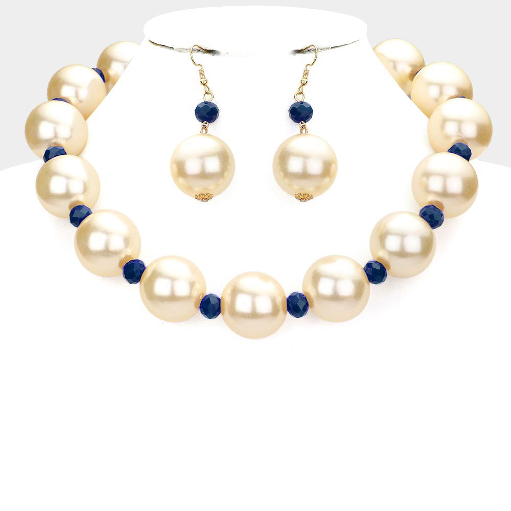 Cream oversized pearls, divided by navy accent beads, and matching drop earrings, statement necklace set, displayed on a white jewelry bust.