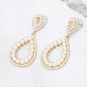 Cream pave pearl open teardrop earrings on gold displayed on white marble background
