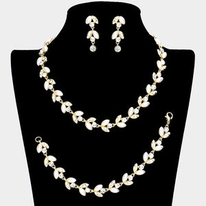 Cream pearl and crystal bridal jewelry set in a gold finish featuring a coordinating necklace, drop earrings, and bracelet with leaf-inspired accents, displayed on a black jewelry bust.