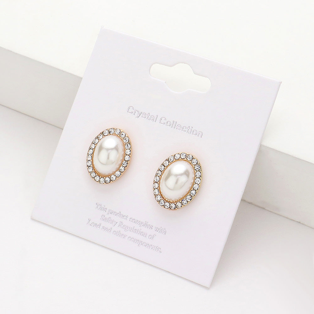 Cream faux pearl oval stud earrings surrounded by clear rhinestones on gold-tone metal, displayed on a white jewelry card.