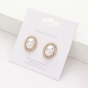 Cream faux pearl oval stud earrings surrounded by clear rhinestones on gold-tone metal, displayed on a white jewelry card.
