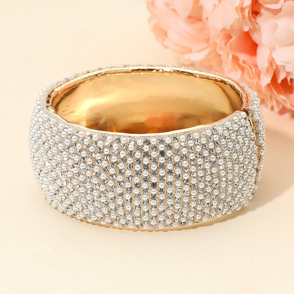 Cream pearl wide rhinestone hinged evening bangle bracelet on gold with pavé crystal design on a peach background