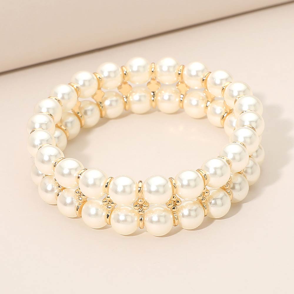 Double row cream pearl bridal stretch bracelet with gold spacer accents and layered bead design on a light beige background