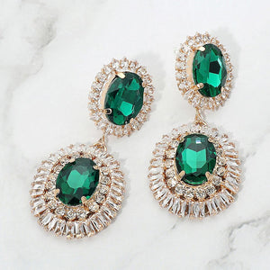 Emerald Green vintage double oval crystal statement earrings in a gold finish featuring two oval emerald green crystals surrounded by sparkling crystal halos, displayed on a white marble background.