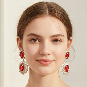 Red vintage double oval crystal statement earrings in a gold finish featuring two oval red crystals surrounded by clear crystal halos, shown here on a model wearing the earrings.