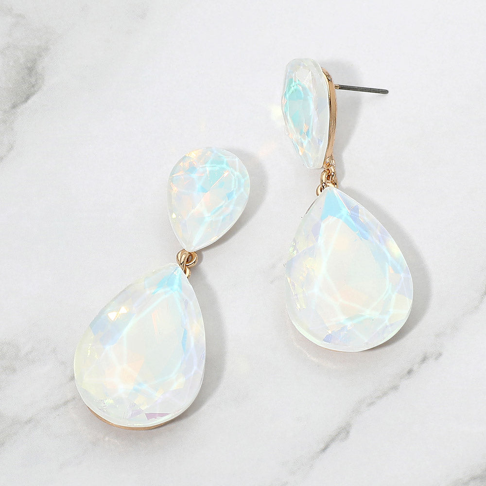 White opal crystal double teardrop dangle earrings on gold displayed on a white marble background.