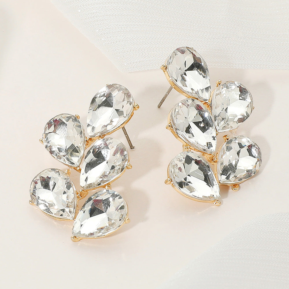 Clear teardrop cluster earrings on gold for weddings or pageants on a light background.