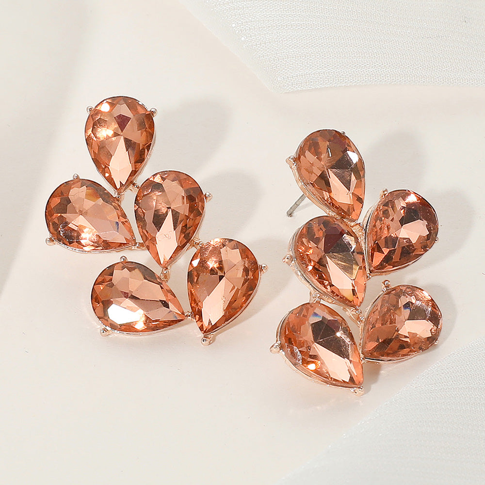 Peach teardrop stone cluster earrings on rose gold for weddings or pageants on a light background.