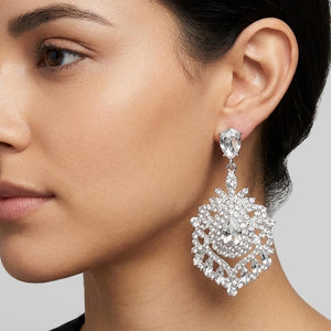 Woman wearing Clear crystal teardrop chandelier statement earrings on silver with an ornate layered crystal design against a neutral background.