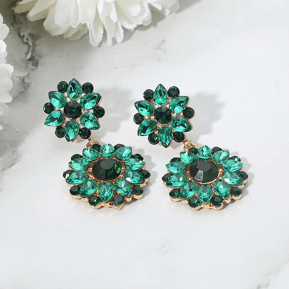 Emerald green floral stone cluster earrings with rhinestones for pageant or prom on a white background