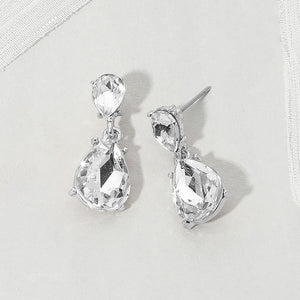 Double teardrop dangle earrings with clear crystals on silver, featuring smaller faceted teardrops above larger teardrop drops, displayed on a white textured surface.