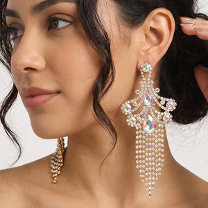 A woman wearing a large ornate AB-Aurora Borealis Crystal statement earring on silver with cascading bead fringe and AB crystal accents against a light gray background.