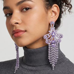 A woman wearing a large ornate Lavender Purple crystal statement earring on silver with cascading bead fringe and clear crystal accents against a light gray background.