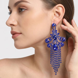 A woman wearing a large ornate Sapphire Royal Blue crystal statement earring with cascading bead fringe and clear crystal accents against a light gray background.