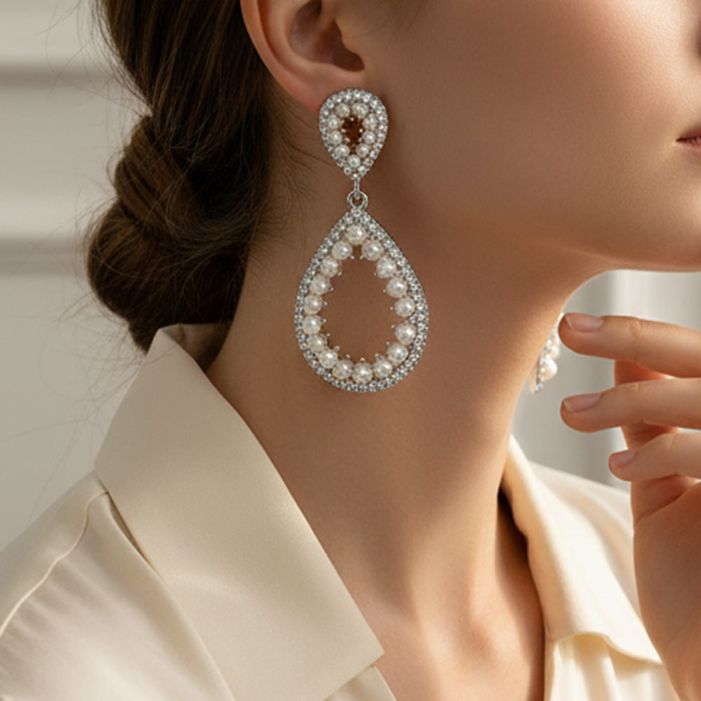 White pave pearl open teardrop earrings on silver displayed on a model's ear
