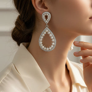 White pave pearl open teardrop earrings on silver displayed on a model's ear