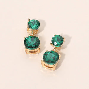 Small emerald green double round little girls pageant drop earrings on gold on a beige background