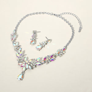 AB crystal teardrop and marquise leaf necklace set on silver with matching earrings, iridescent statement jewelry for bridal, prom, and evening wear on a beige background
