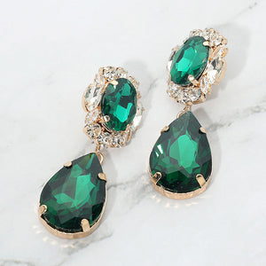 Emerald green oval and teardrop earrings with clear crystal accents on gold on a white marble background