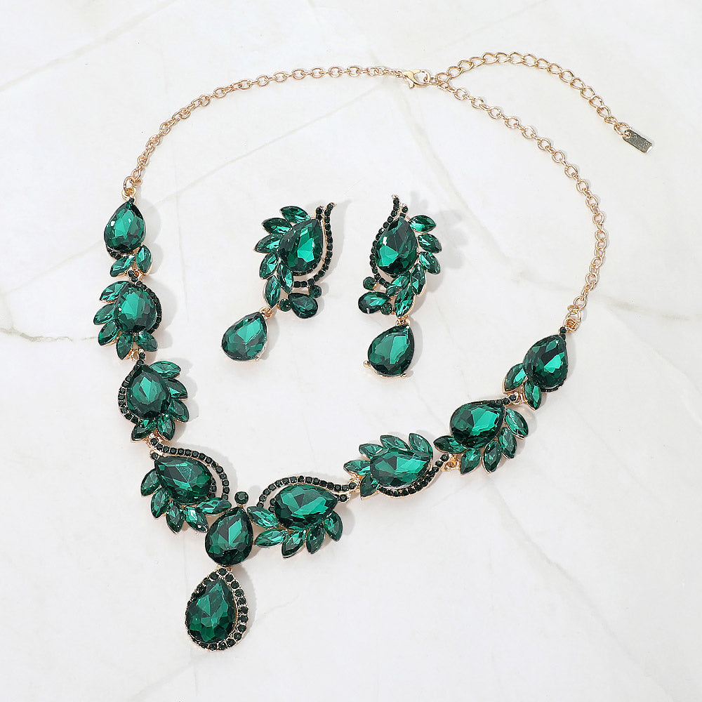 Emerald green teardrop formal necklace and matching earrings set on gold displayed on a white background.