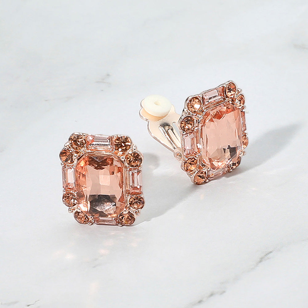Peach emerald cut clip-on earrings on rose gold for prom, weddings, or evening wear on a grey and white granite background