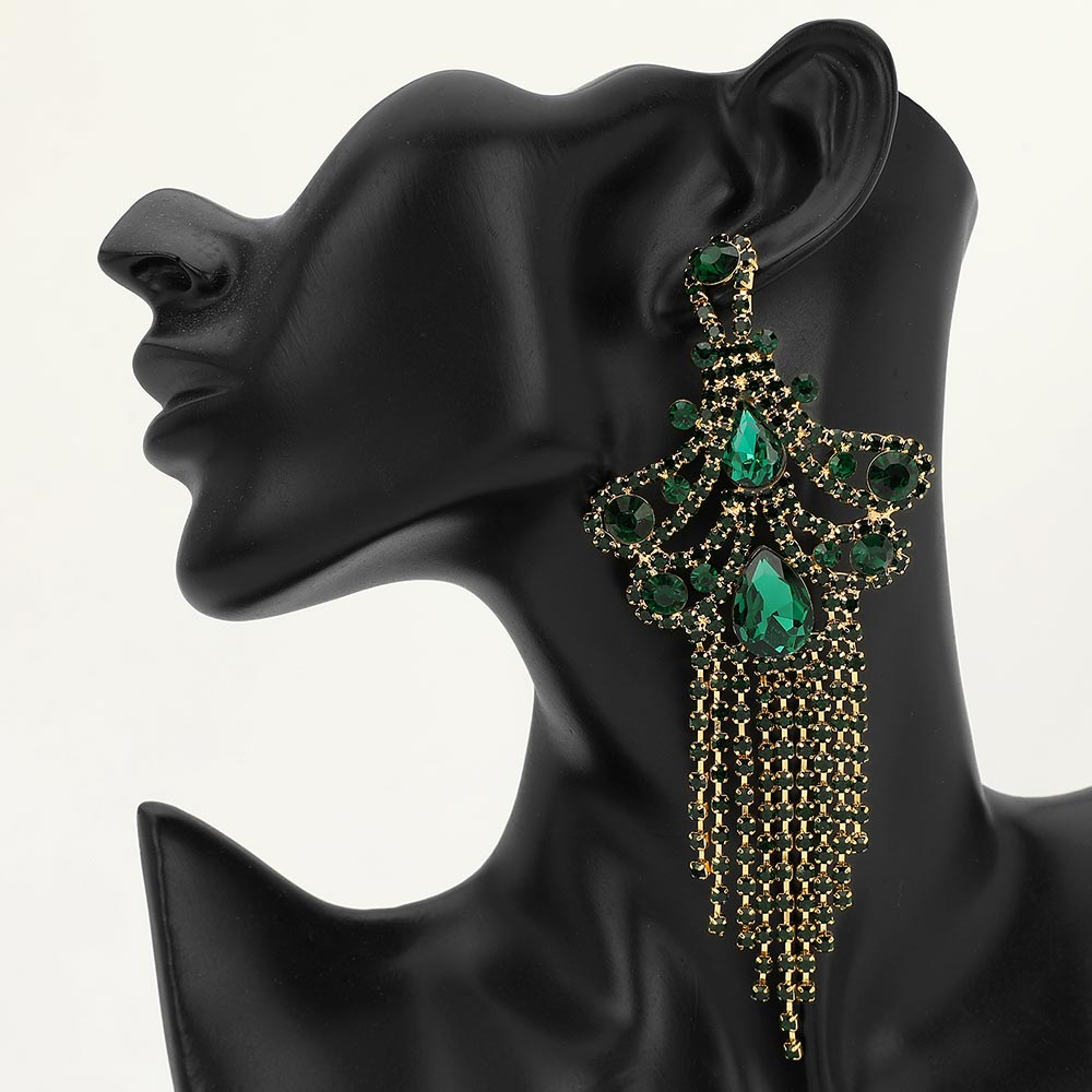 A large ornate Emerald Green crystal statement earring on gold with cascading bead fringe and clear crystal accents on a black earring mannequin.