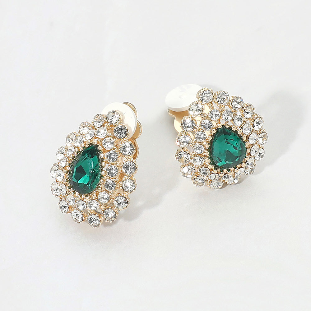Emerald green teardrop rhinestone halo clip-on earrings with silver-tone setting and crystal cluster design on a light gray background