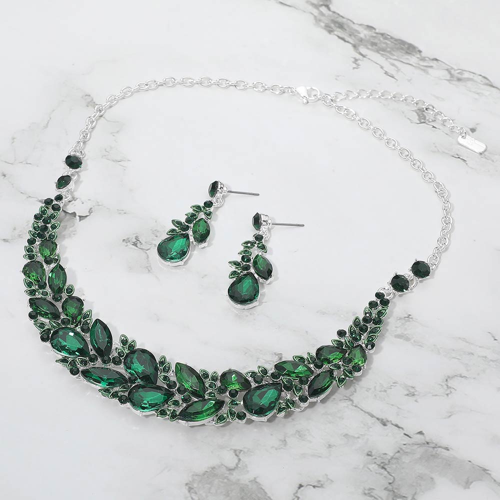 Emerald green marquise crystal cluster necklace set on silver with matching earrings, elegant statement jewelry for prom and evening wear on a marble background
