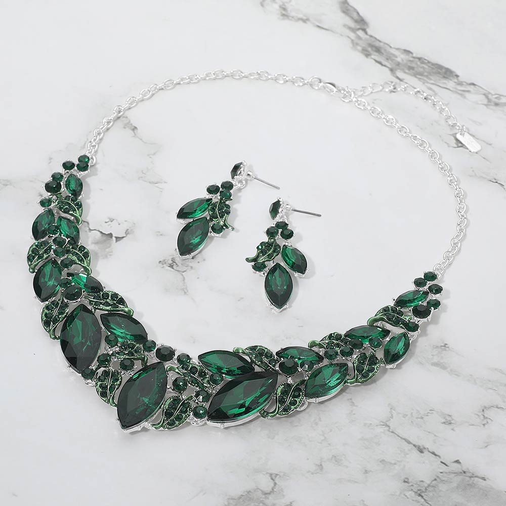 Emerald green marquise leaf crystal necklace set on silver with matching earrings, elegant statement jewelry for prom and evening wear on a marble background