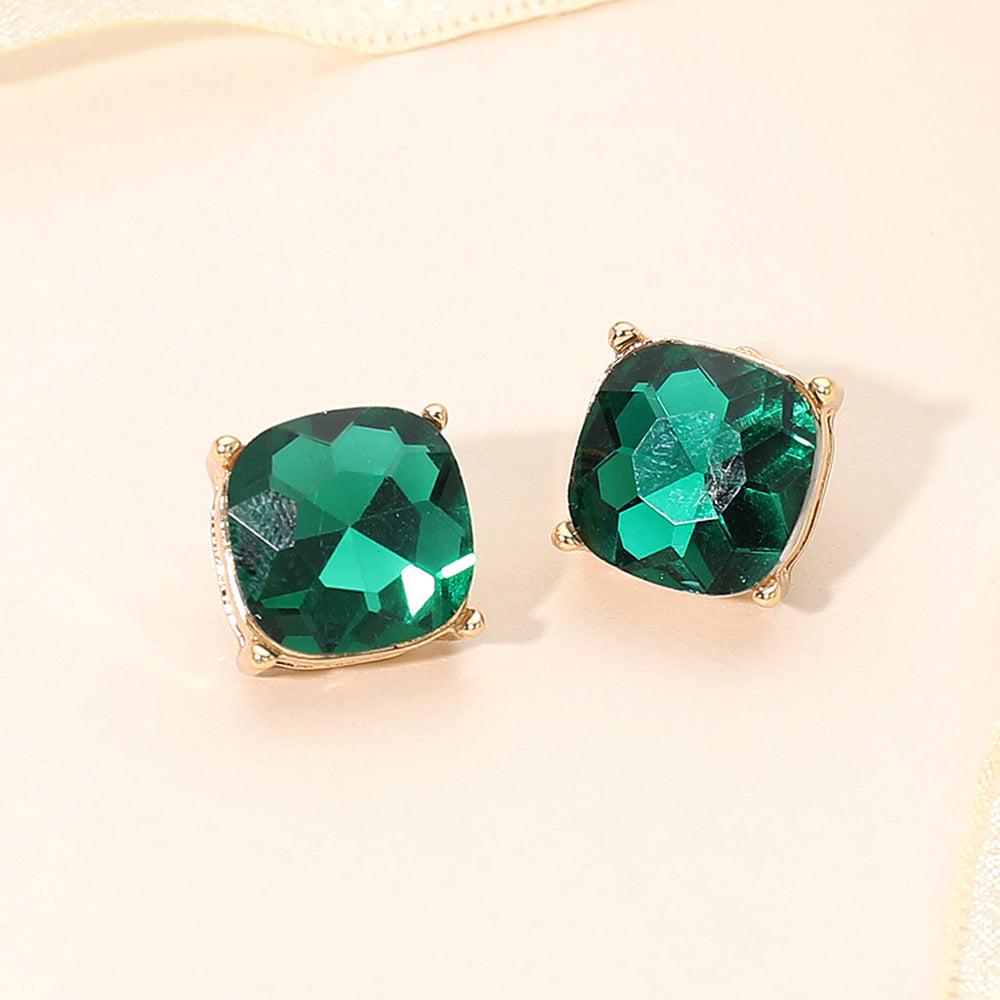 Emerald emerald green square cushion stud earrings on gold on light beige background