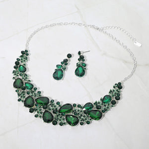Emerald green teardrop leaf branch statement necklace set on silver on a white marble background