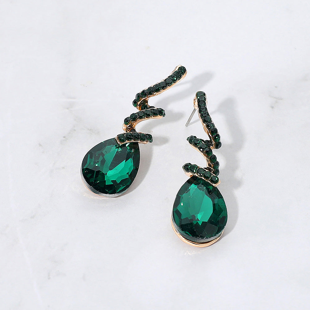 Emerald green teardrop swirl crystal earrings for girls pageant or beauty walk wear on a white background