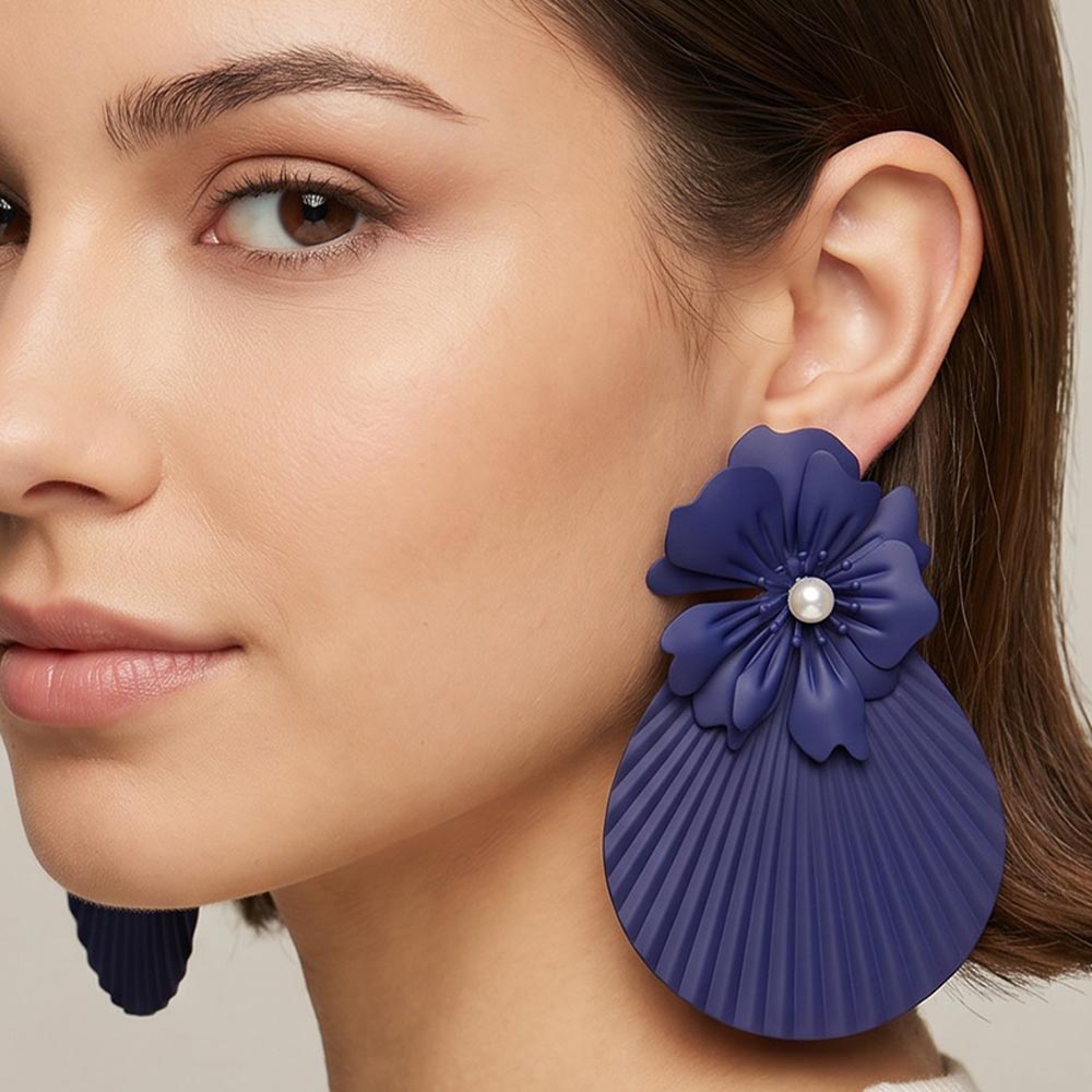 Model wearing oversized royal blue flower fan statement earrings with layered floral tops and pleated fan drops, showing their 4.25-inch length and bold scale.