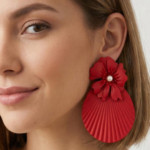 Model wearing oversized red flower fan statement earrings with layered floral tops and pleated fan drops, showing their 4.25-inch length and bold scale.