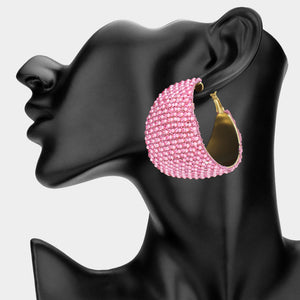 Pink bling pavé crystal wide hoop earrings on gold-tone metal with dense faceted rhinestone coverage and omega backs, displayed on a black mannequin profile.