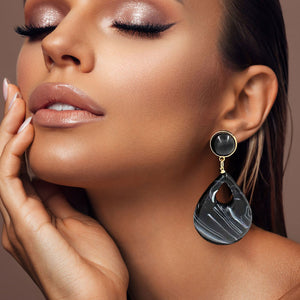 Black resin teardrop cutout dangle earrings on a pretty lady on a neutral background — bold modern 3.25" fashion statement jewelry.
