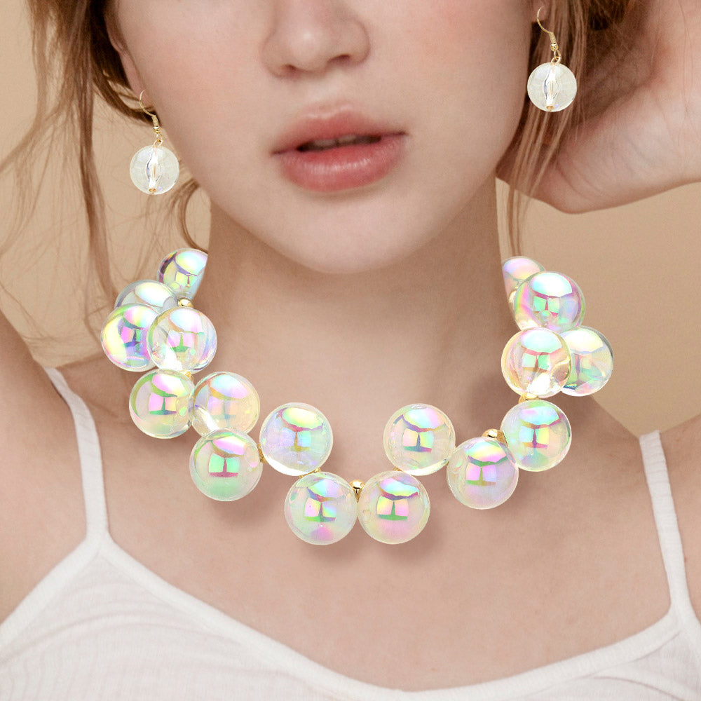 Chunky clear on gold iridescent balls/spheres necklace with matching earrings on the neck of a girl wearing a white shirt
