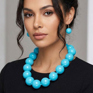 Model wearing turquoise chunky ball beaded statement necklace set with oversized round beads and matching drop earrings.