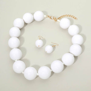White chunky ball beaded statement necklace set with oversized round beads and matching drop earrings, displayed on a light cream background.