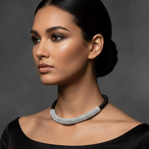 A woman wearing a black and clear crystal beaded choker necklace with a textured microbeaded front section against a dark gray background.
