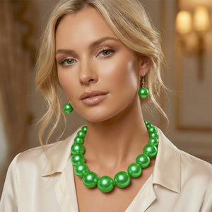 Green Oversized Graduated Pearl Glossy Statement Necklace Set on gold shown on a woman on a blurry background. 